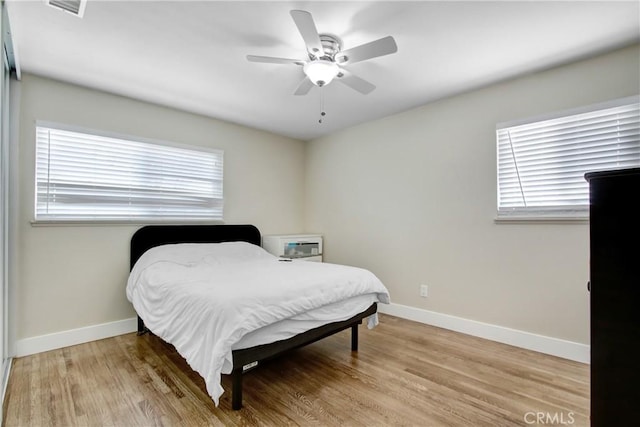 bedroom featuring baseboards, a ceiling fan, light wood finished floors, and visible vents