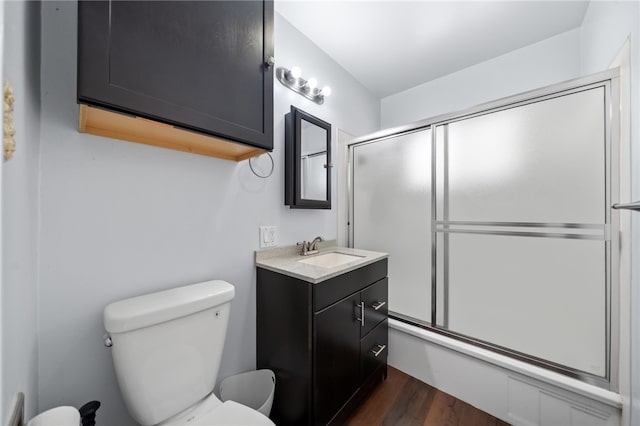 bathroom with vanity, toilet, wood finished floors, and shower / bath combination with glass door