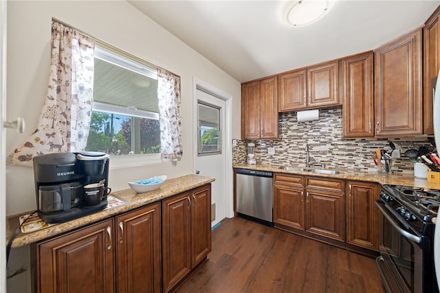 kitchen with stainless steel dishwasher, decorative backsplash, a sink, dark wood finished floors, and black range with gas cooktop