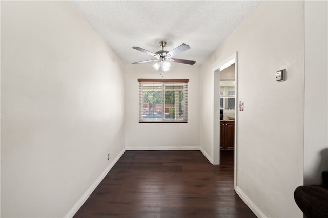 spare room featuring baseboards, ceiling fan, dark wood finished floors, and a textured ceiling