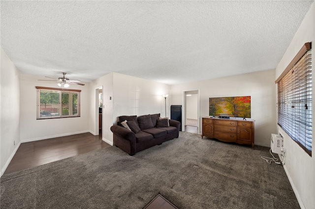 living area featuring dark colored carpet, a textured ceiling, ceiling fan, and baseboards