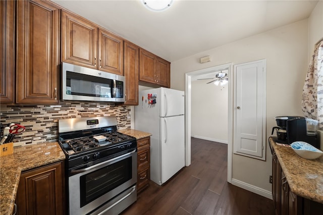 kitchen with decorative backsplash, dark wood-type flooring, light stone counters, a ceiling fan, and stainless steel appliances