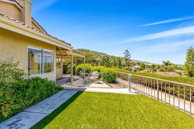 view of yard with a patio, fence, and a mountain view