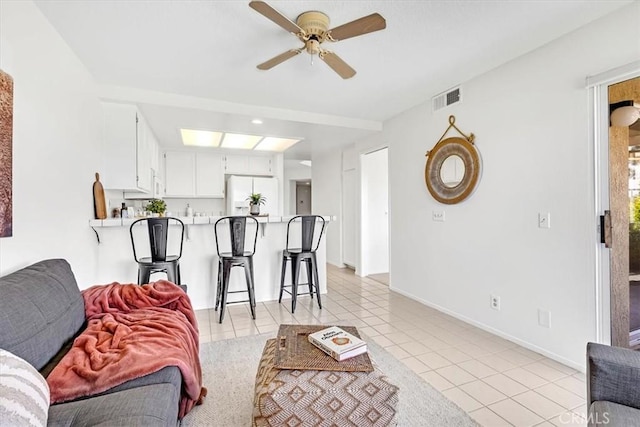 living room with baseboards, a ceiling fan, light tile patterned flooring, and visible vents