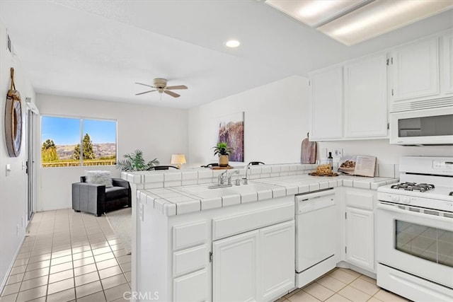 kitchen featuring light tile patterned flooring, ceiling fan, white appliances, a peninsula, and open floor plan