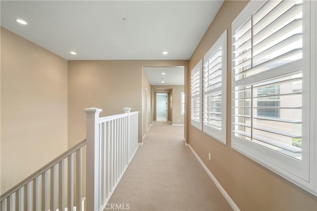 hallway with recessed lighting, baseboards, light colored carpet, and an upstairs landing