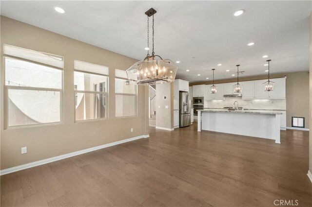 interior space featuring stainless steel appliances, baseboards, white cabinetry, and tasteful backsplash