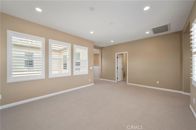 empty room featuring baseboards, light colored carpet, and visible vents