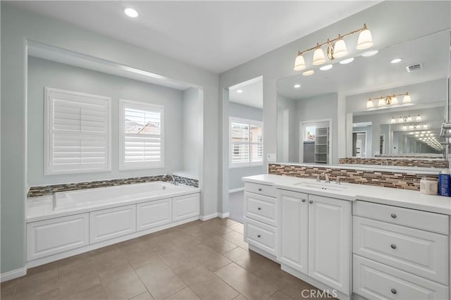 bathroom featuring visible vents, vanity, a garden tub, baseboards, and tasteful backsplash