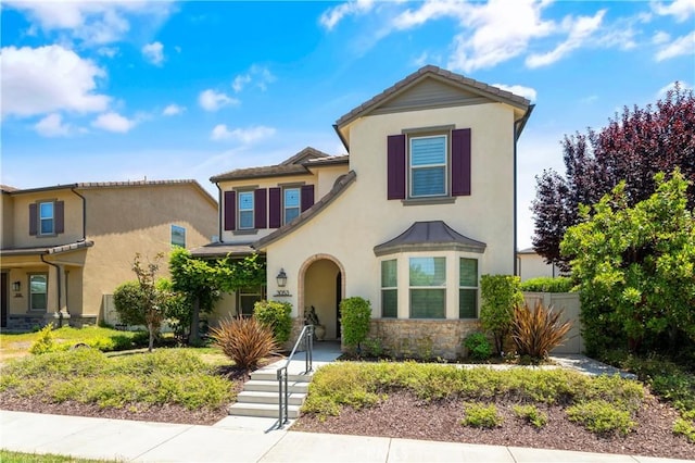 traditional-style home featuring fence, a tile roof, stone siding, and stucco siding