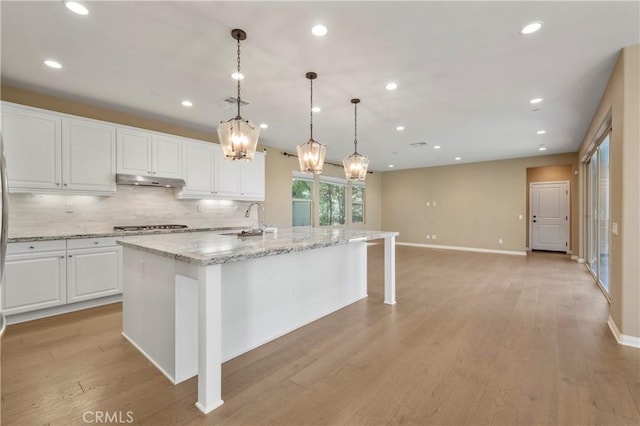 kitchen featuring light wood-style floors, recessed lighting, white cabinetry, a sink, and backsplash