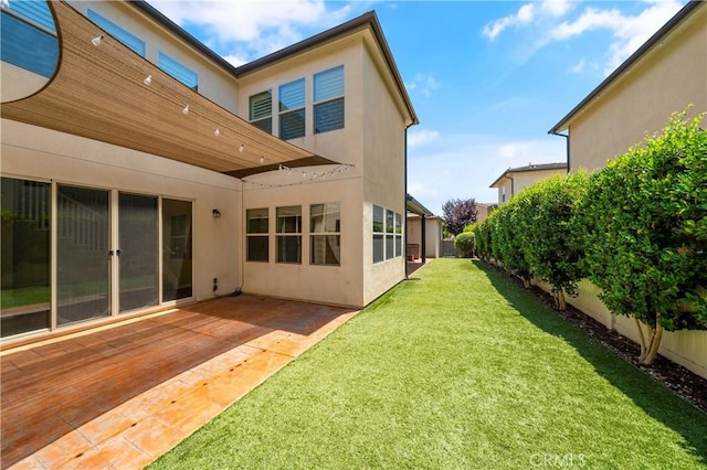rear view of house featuring a yard, a fenced backyard, and stucco siding