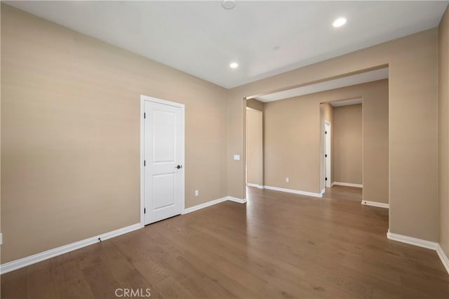empty room with baseboards, recessed lighting, and wood finished floors