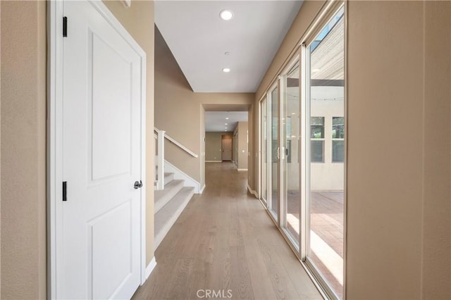 corridor featuring light wood-type flooring, recessed lighting, and stairway