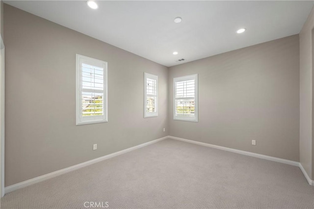 empty room featuring baseboards, visible vents, recessed lighting, and light colored carpet