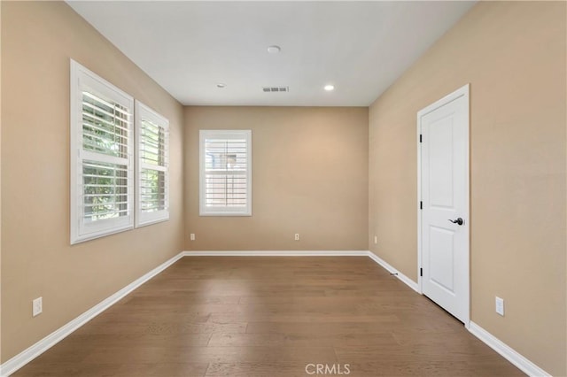 empty room featuring baseboards, recessed lighting, wood finished floors, and visible vents