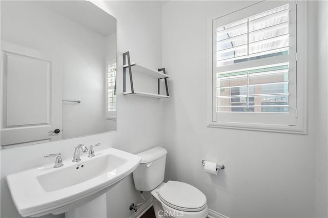 half bathroom featuring baseboards, a sink, and toilet