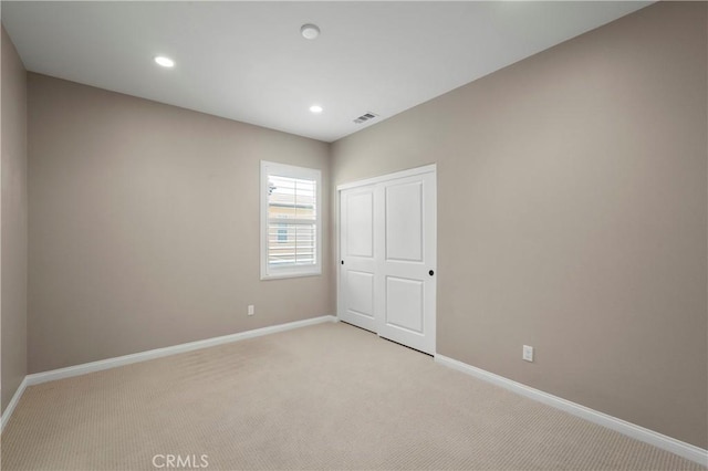 unfurnished bedroom featuring baseboards, visible vents, and light carpet