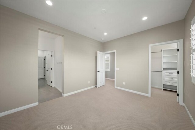unfurnished bedroom featuring carpet floors, baseboards, and a spacious closet