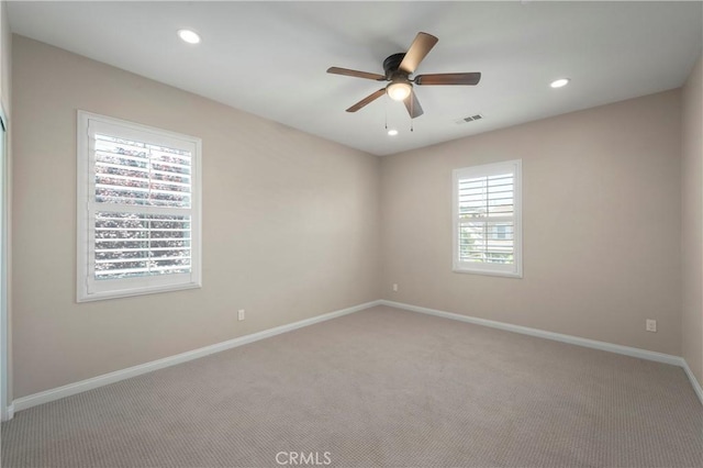 unfurnished room with visible vents, carpet flooring, baseboards, and a ceiling fan