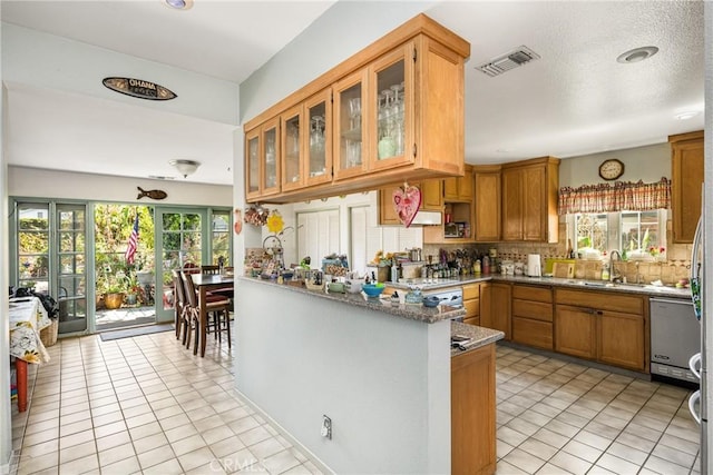 9712 Russell Ave, Garden Grove, CA 92844 - kitchen with a sink, brown cabinetry, stainless steel dishwasher, visible vents, and tasteful backsplash