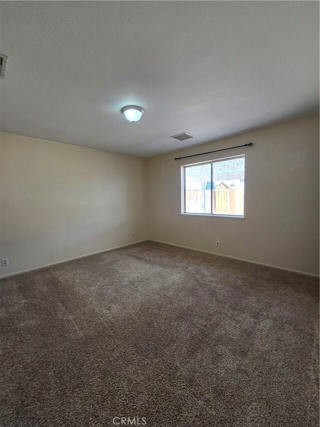 carpeted empty room featuring visible vents and baseboards