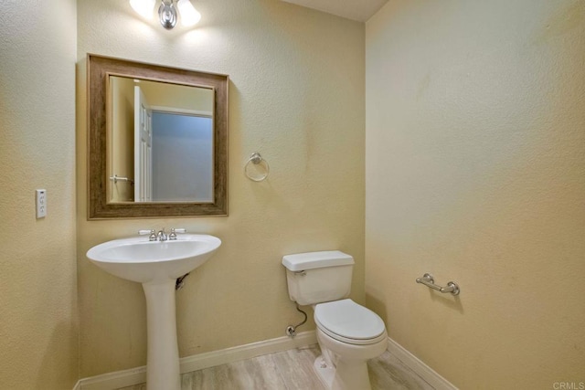 bathroom with baseboards, toilet, and wood finished floors