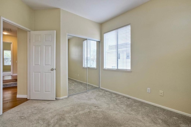 unfurnished bedroom with baseboards, carpet, a closet, and multiple windows