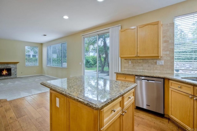 kitchen featuring recessed lighting, a center island, light stone counters, light wood finished floors, and dishwasher