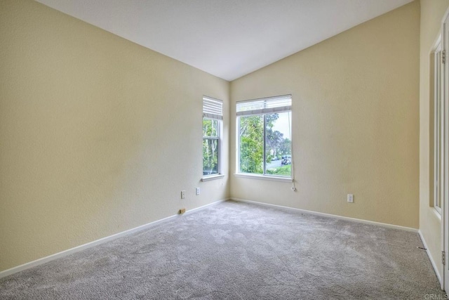 carpeted empty room with baseboards and lofted ceiling