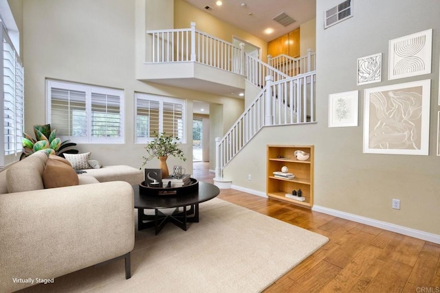 living room with baseboards, visible vents, wood finished floors, and a high ceiling