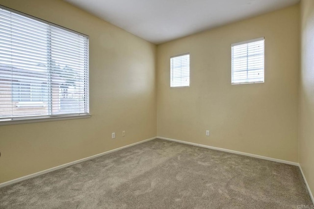 carpeted spare room featuring baseboards