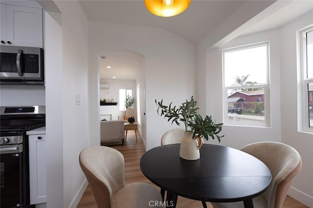11714 S Spring St, Los Angeles, CA 90061 - dining room with baseboards, wood finished floors, an AC wall unit, and a wealth of natural light