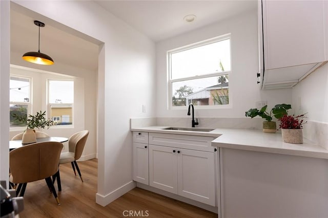 11714 S Spring St, Los Angeles, CA 90061 - bar with baseboards, hanging light fixtures, a sink, and light wood-style floors