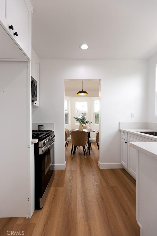 11714 S Spring St, Los Angeles, CA 90061 - kitchen with stainless steel gas range oven, recessed lighting, light countertops, white cabinetry, and light wood-type flooring