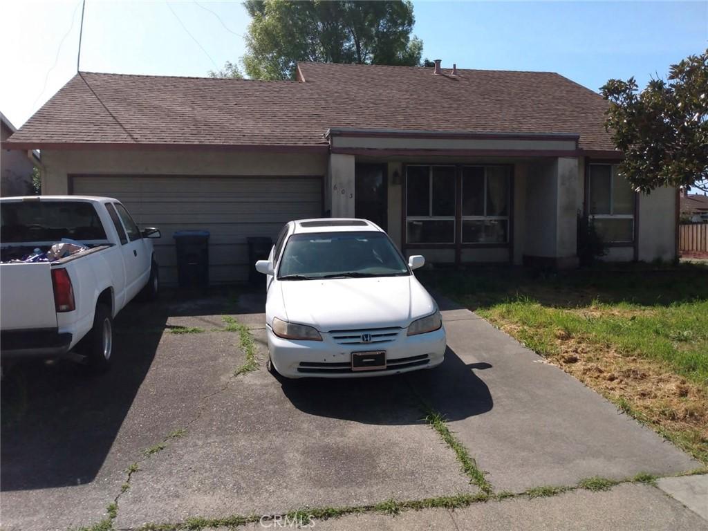 ranch-style home with an attached garage, driveway, and roof with shingles