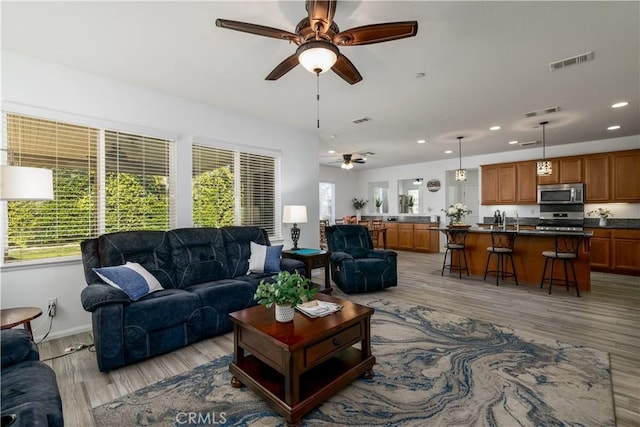 living room featuring recessed lighting, ceiling fan, light wood finished floors, and visible vents
