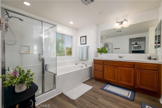 full bath featuring a bath, visible vents, a stall shower, wood finished floors, and vanity