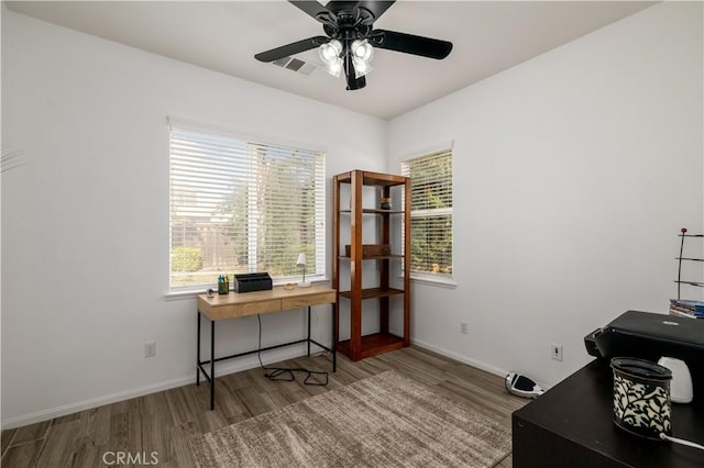 home office featuring visible vents, a ceiling fan, baseboards, and wood finished floors