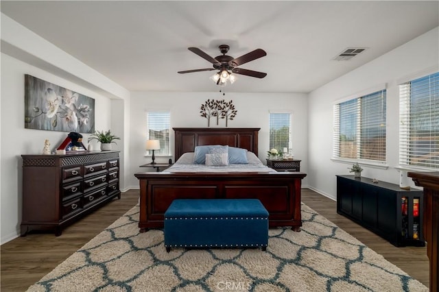 bedroom with a ceiling fan, baseboards, visible vents, and wood finished floors