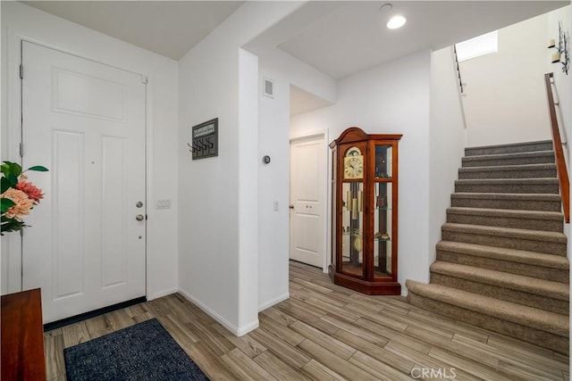 entrance foyer with visible vents, baseboards, light wood finished floors, and stairs