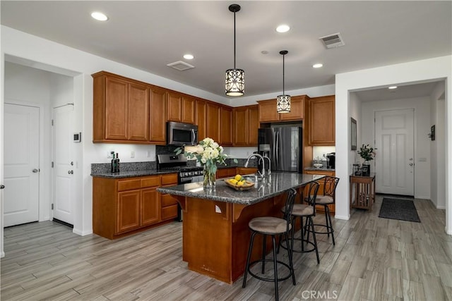 kitchen featuring light wood-type flooring, brown cabinets, and stainless steel appliances