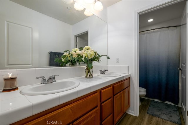 full bathroom with double vanity, a sink, wood finished floors, and toilet