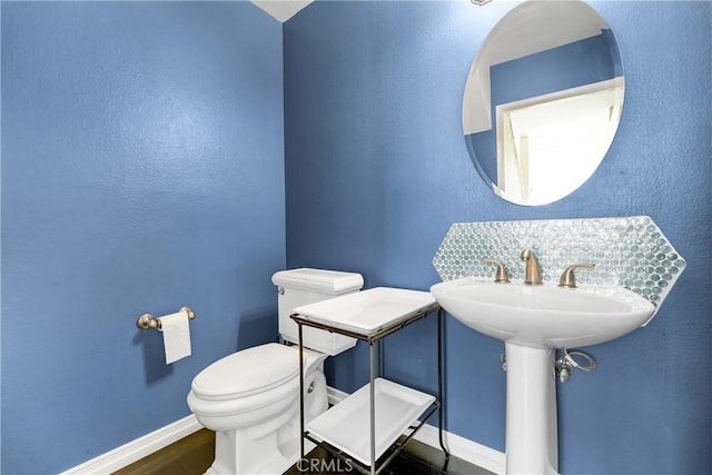 half bathroom featuring baseboards and toilet