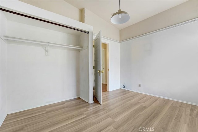 unfurnished bedroom with baseboards, wood finished floors, and a closet