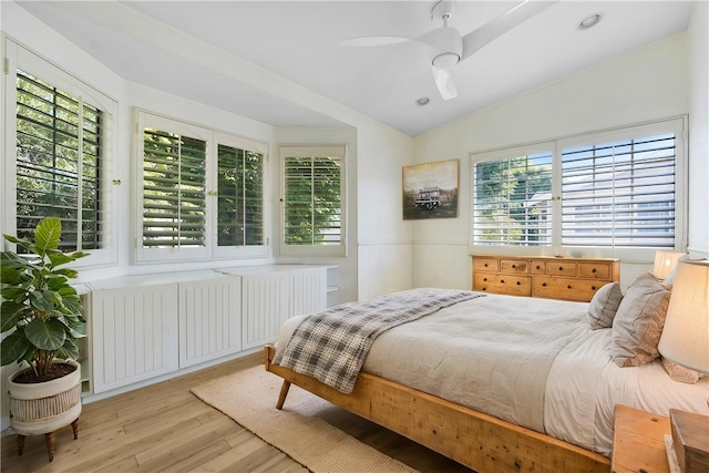 bedroom with multiple windows, wood finished floors, and radiator