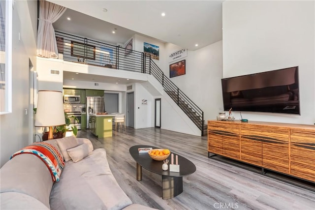 1055 S Serrano Ave Unit 502, Los Angeles, CA 90006 - living area with recessed lighting, wood finished floors, a towering ceiling, visible vents, and stairway