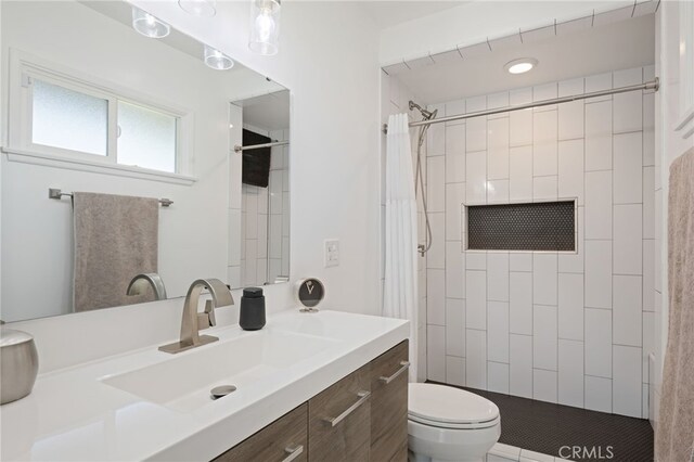 full bathroom featuring vanity, a tile shower, and toilet