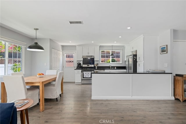 kitchen with visible vents, dark countertops, white cabinetry, a sink, and appliances with stainless steel finishes