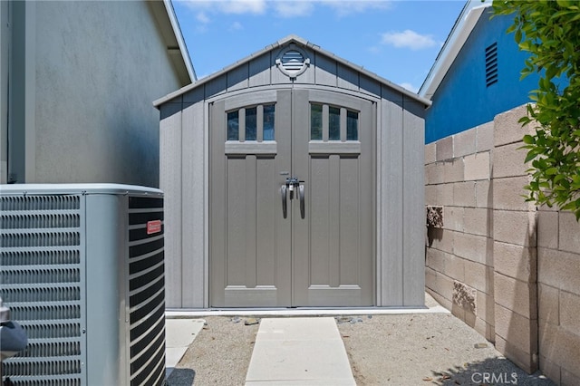 view of shed featuring central AC unit and fence